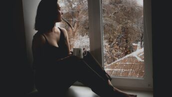 Girl stirring out a window she is sitting against