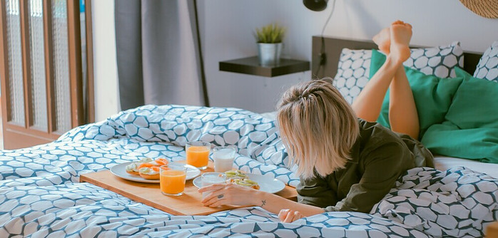 girl on a bed with a tray of nutritious food